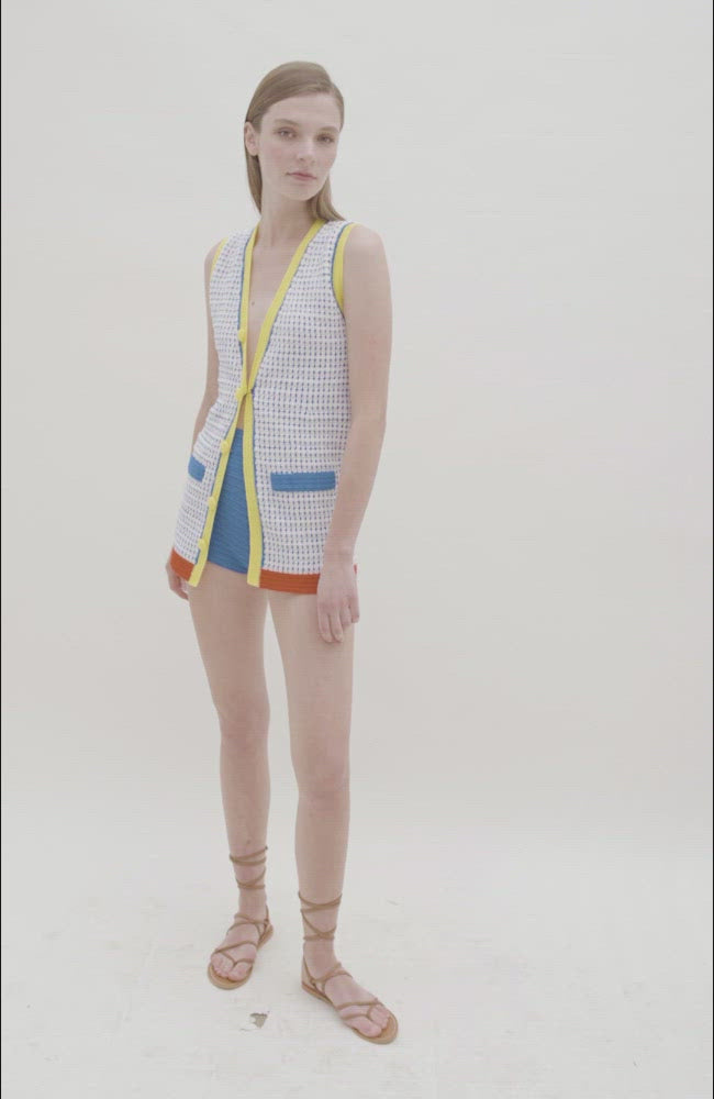 video of blue and white knit long vest with red and yellow trim and yellow buttons